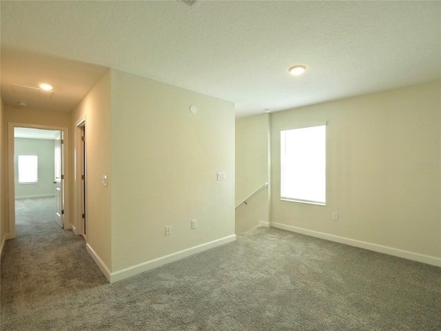 carpeted spare room with a textured ceiling