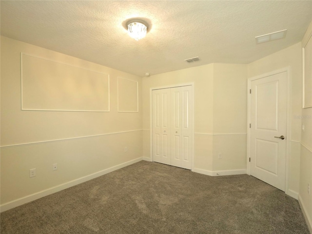 unfurnished bedroom with a textured ceiling, dark carpet, and a closet