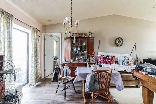 dining space featuring light hardwood / wood-style flooring, lofted ceiling, a textured ceiling, and an inviting chandelier