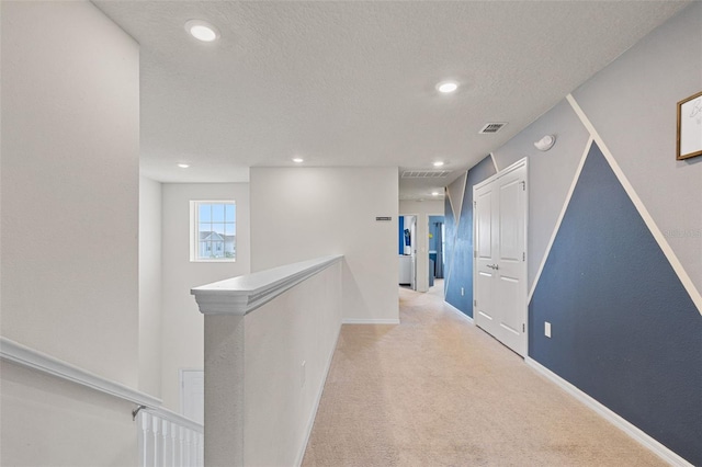 corridor featuring light colored carpet and a textured ceiling