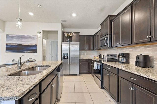 kitchen featuring pendant lighting, sink, light tile patterned floors, an island with sink, and stainless steel appliances