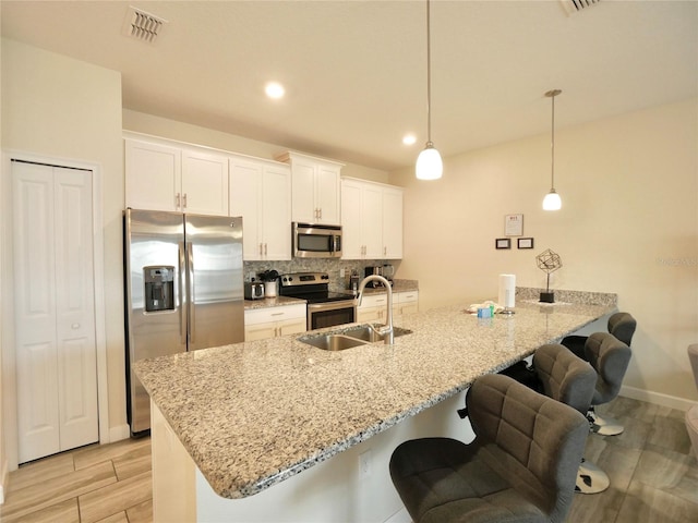 kitchen featuring sink, white cabinets, pendant lighting, and appliances with stainless steel finishes