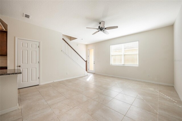 spare room featuring ceiling fan, light tile patterned floors, and a textured ceiling