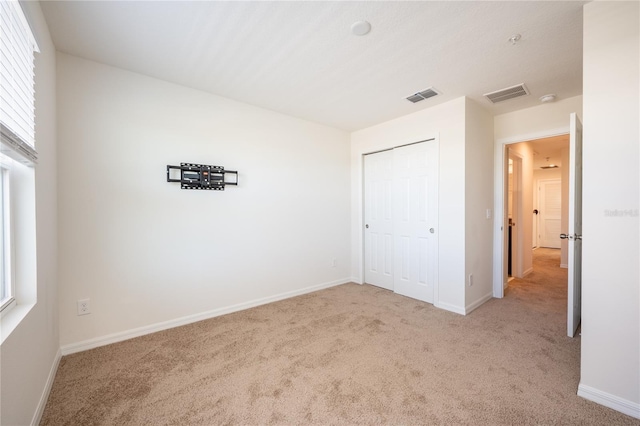 unfurnished bedroom featuring light colored carpet and a closet