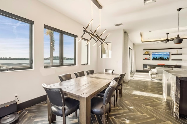 dining area featuring dark parquet flooring and ceiling fan with notable chandelier