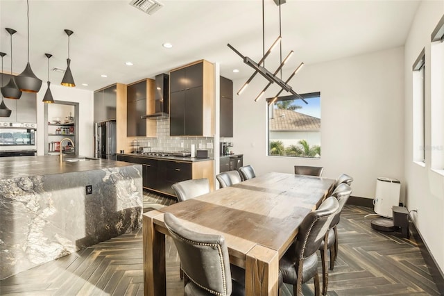 dining room featuring dark parquet flooring, sink, and an inviting chandelier