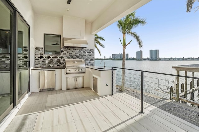 exterior space with grilling area, sink, a water view, and exterior kitchen