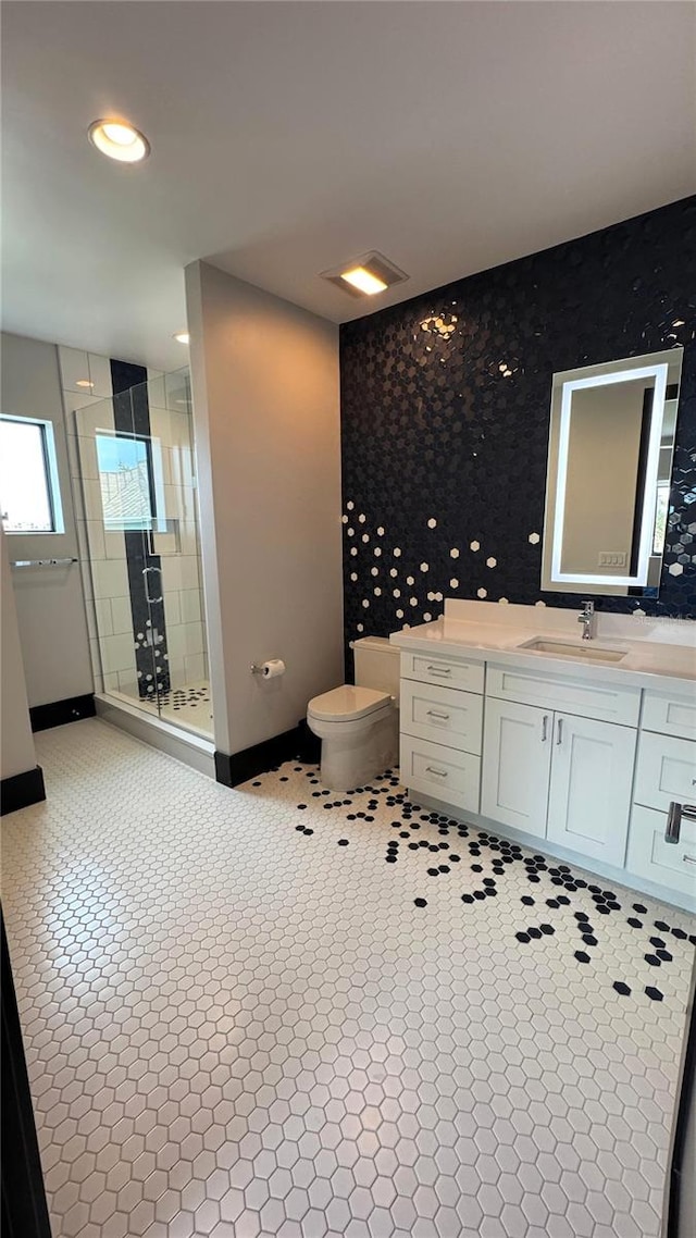 bathroom with tile patterned flooring, vanity, toilet, and walk in shower