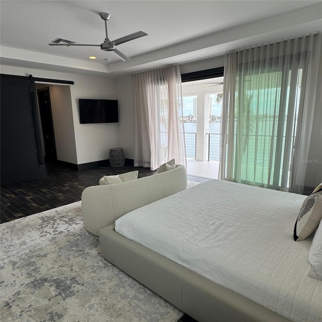 bedroom with access to exterior, hardwood / wood-style floors, a barn door, and ceiling fan