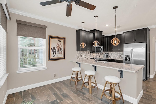 kitchen featuring a breakfast bar area, light stone countertops, tasteful backsplash, decorative light fixtures, and stainless steel appliances