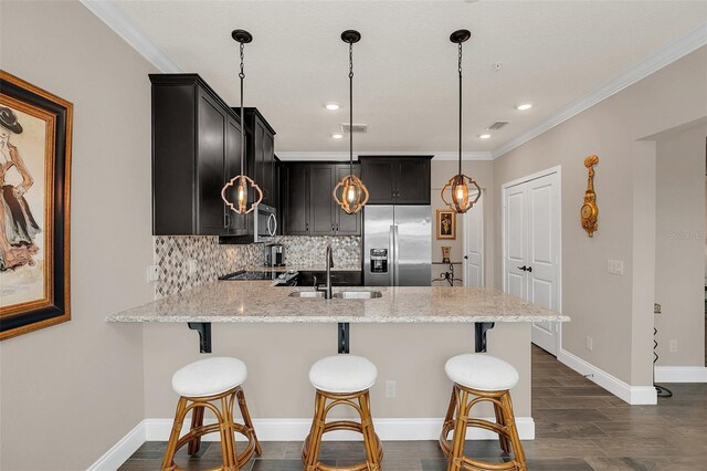 kitchen with light stone countertops, a kitchen breakfast bar, pendant lighting, decorative backsplash, and appliances with stainless steel finishes