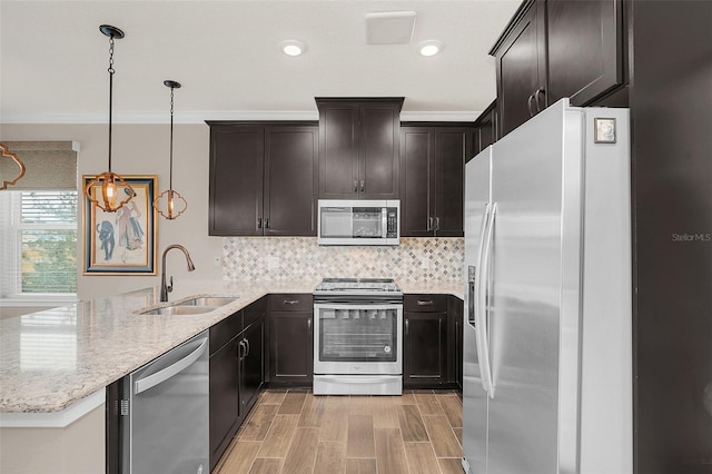 kitchen featuring sink, hanging light fixtures, light stone counters, kitchen peninsula, and appliances with stainless steel finishes