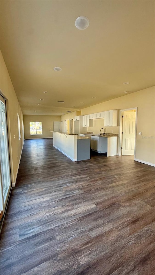 unfurnished living room with dark hardwood / wood-style flooring and sink