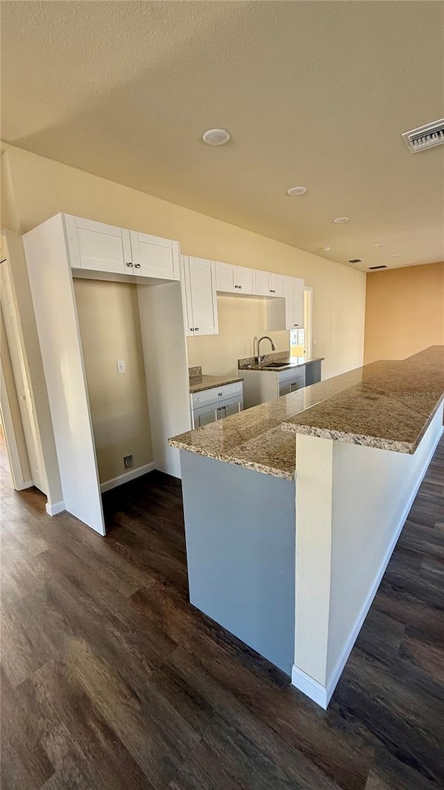 kitchen featuring white cabinets, dark hardwood / wood-style flooring, light stone counters, and sink