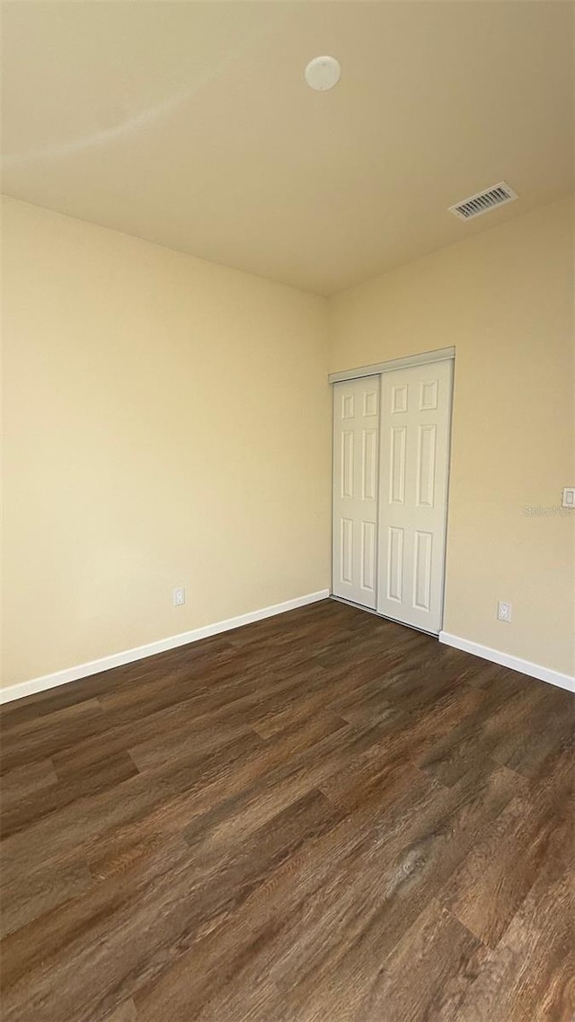 unfurnished bedroom featuring dark hardwood / wood-style floors and a closet