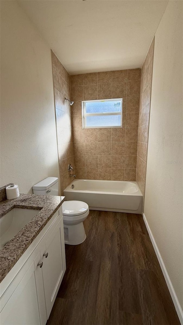 full bathroom featuring hardwood / wood-style flooring, vanity, toilet, and tiled shower / bath