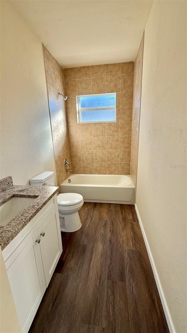 full bathroom with tiled shower / bath combo, toilet, wood-type flooring, and vanity