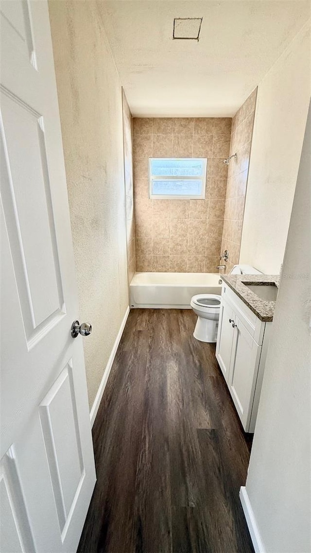 full bathroom with hardwood / wood-style floors, vanity, toilet, and tiled shower / bath combo