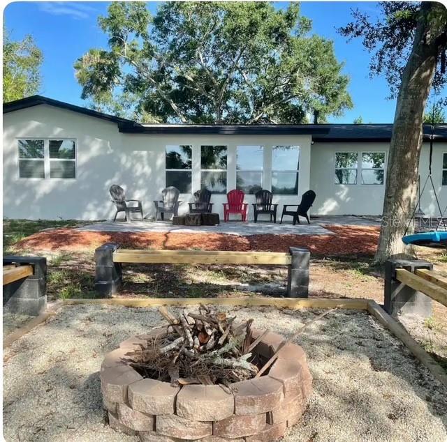 back of property featuring a patio and an outdoor fire pit