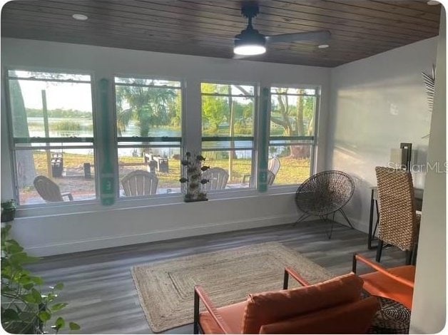 sunroom with a healthy amount of sunlight, a water view, and wooden ceiling