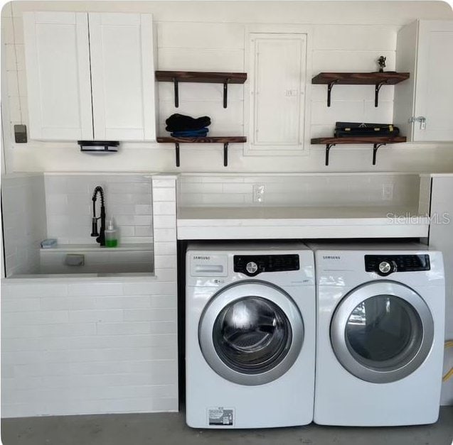 laundry area with washer and dryer, cabinets, and sink