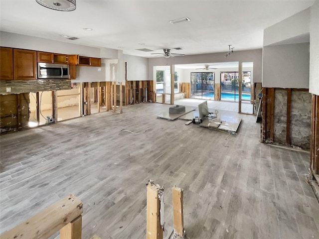 unfurnished living room featuring ceiling fan and light wood-type flooring