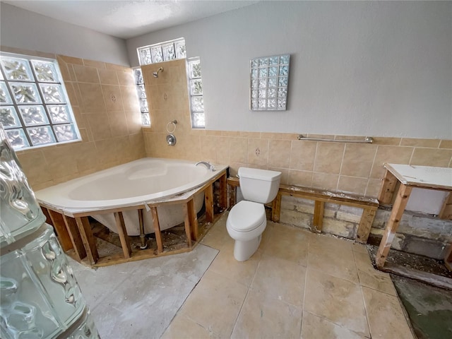 bathroom with a bathing tub, toilet, and tile walls