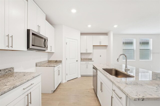 kitchen with light stone counters, sink, stainless steel appliances, and white cabinets