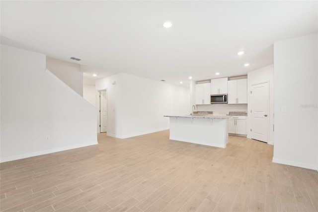 unfurnished living room with sink and light hardwood / wood-style floors