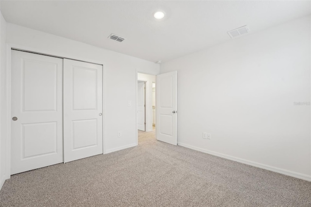 unfurnished bedroom with light colored carpet and a closet