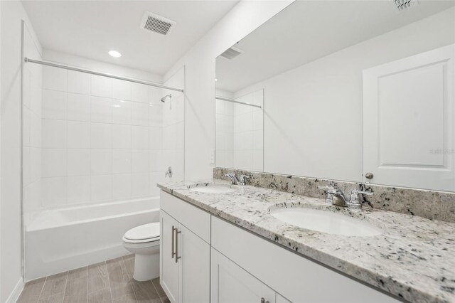 full bathroom featuring tiled shower / bath, vanity, and toilet