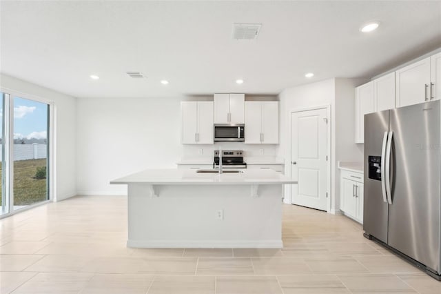 kitchen featuring appliances with stainless steel finishes, sink, a kitchen island with sink, and white cabinets