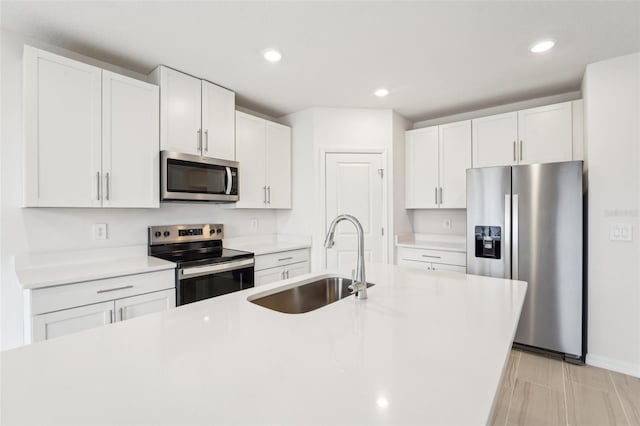 kitchen featuring an island with sink, appliances with stainless steel finishes, sink, and white cabinets