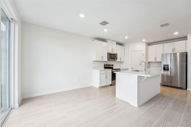 kitchen featuring sink, appliances with stainless steel finishes, a kitchen breakfast bar, an island with sink, and white cabinets