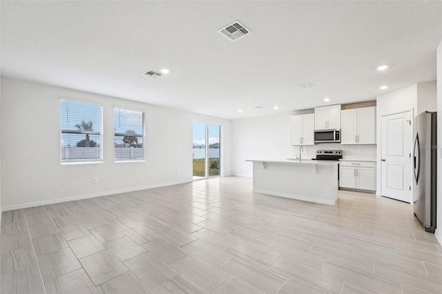 kitchen with sink, an island with sink, white cabinets, and appliances with stainless steel finishes