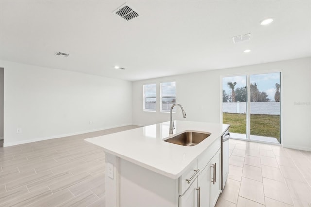 kitchen with a kitchen island with sink, sink, stainless steel dishwasher, and white cabinets