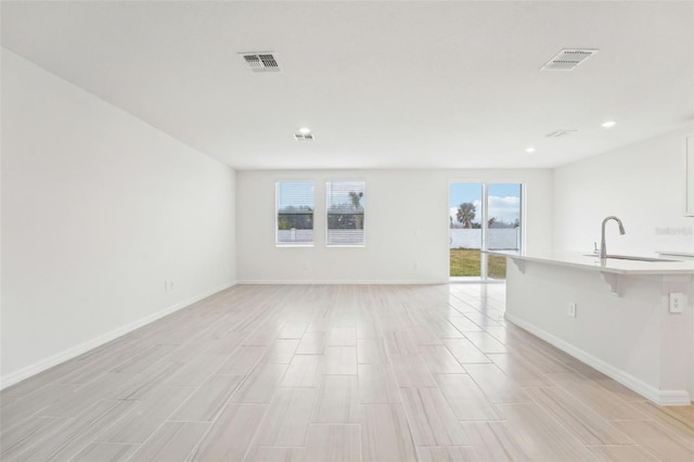 unfurnished living room featuring sink and plenty of natural light