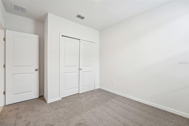 unfurnished bedroom featuring light carpet and a closet