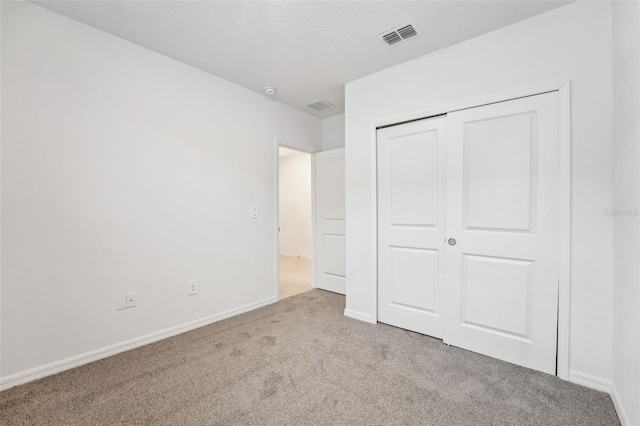 unfurnished bedroom with light carpet and a closet