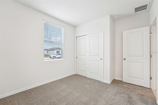 unfurnished bedroom with light colored carpet and a closet