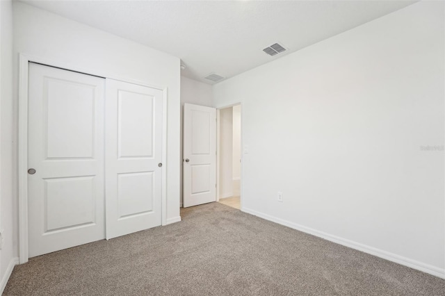 unfurnished bedroom featuring light carpet and a closet