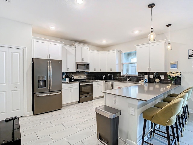 kitchen with decorative light fixtures, appliances with stainless steel finishes, and white cabinetry