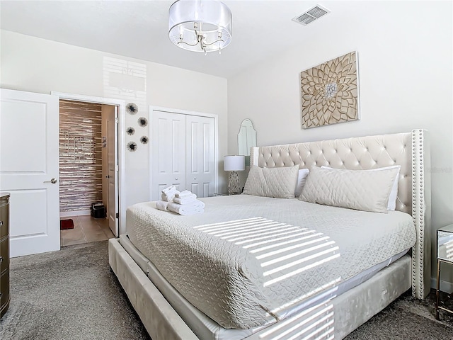 bedroom with a closet, dark carpet, and a notable chandelier