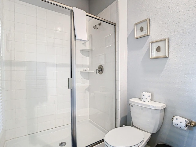 bathroom with a shower with shower door and toilet