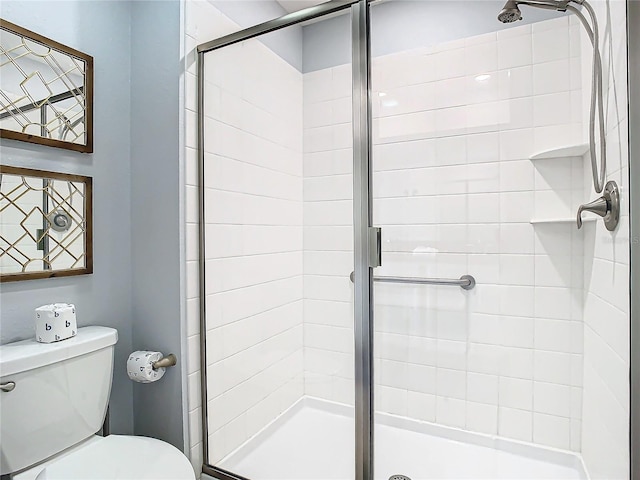 bathroom featuring a shower with shower door and toilet