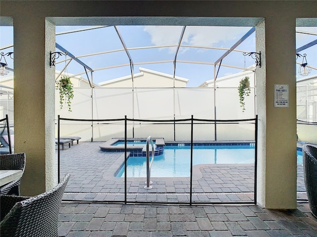 view of pool with glass enclosure, a patio area, and an in ground hot tub