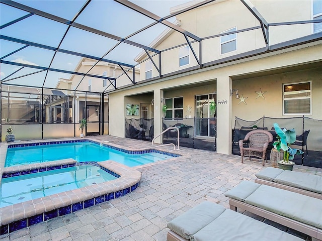 view of pool with glass enclosure, a patio area, and an in ground hot tub