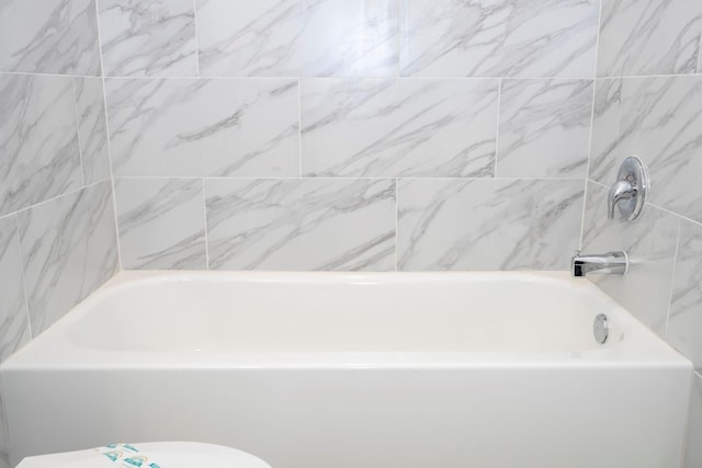 bathroom featuring a washtub and toilet