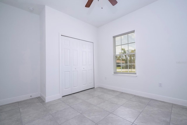 unfurnished bedroom featuring ceiling fan, light tile patterned flooring, and a closet