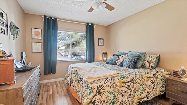 bedroom featuring hardwood / wood-style flooring, ceiling fan, and a textured ceiling